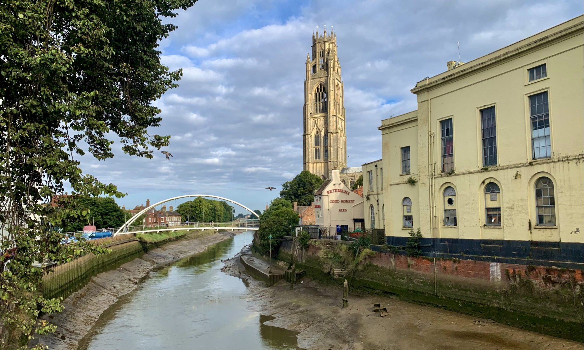 A view along the River Witham including the historic St. Botolph’s church, known as the Boston Stump, in Boston, Lincolnshire, England. Boston, UK - September 17, 2021: A view along the River Witham flowing through Boston in Lincolnshire, UK.